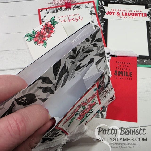 A hand holds a black and white floral handmade card with a pocket, containing white inserts. Other handmade cards decorated with flowers and uplifting messages like “Thank you for being the best” and “You bring so much joy & laughter to my life” are visible in the background. To read more, visit Patty Stamps (pattystamps.com)