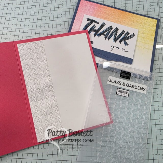 A pink card with an embossed geometric pattern sits on a grid surface. Nearby are a clear embossing folder labeled “GLASS & GARDENS” and a blue “THANK YOU” card decorated with an ombre background and the same embossed geometric design. To read more, visit Patty Stamps (pattystamps.com)