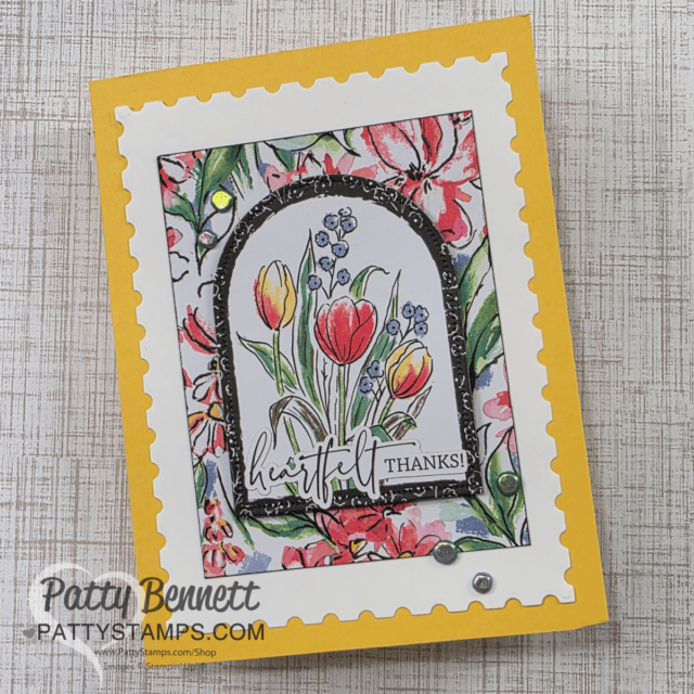 A handmade greeting card featuring a colorful floral design. The center shows tulips and bluebells in a decorative frame. The card has a yellow border and a "heartfelt thanks!" message. Two small gems embellish the design. Memories & More cards make this easy!! To read more, visit Patty Stamps (pattystamps.com)