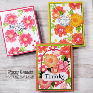 Three handmade floral greeting cards are displayed on a wooden surface. Each features bright red, orange, and pink flowers with green leaves. Sentiments read "thankful for you," "oh, happy day!" and "Thanks." The cards have vibrant, colorful borders. To read more, visit Patty Stamps (pattystamps.com)