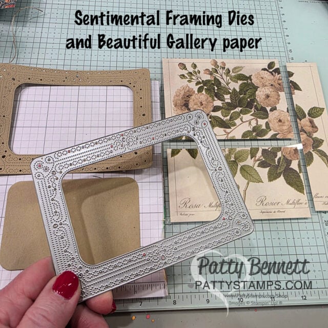 A hand holds a decorative rectangular metal die above craft supplies, including floral and patterned papers, brown envelopes, and a ruler on a grid mat. Large text reads “Sentimental Framing Dies and Beautiful Gallery Paper.”. To read more, visit Patty Stamps (pattystamps.com)