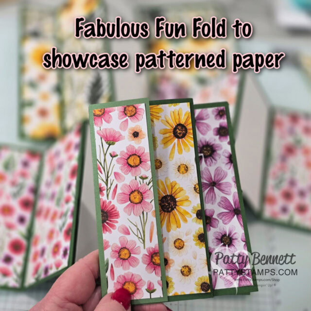 A hand holds a three-panel card with different floral patterned papers: pink flowers, yellow daisies, and purple blooms. Blurred similar cards and papers are in the background. Text reads "Fabulous Fun Fold to showcase patterned paper. To read more, visit Patty Stamps (pattystamps.com)