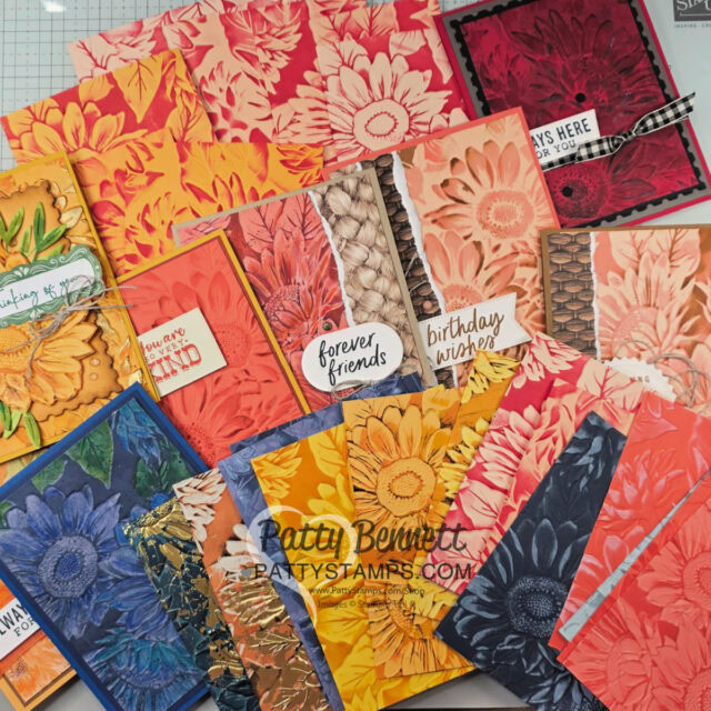 A variety of handmade greeting cards decorated with embossed sunflower designs in warm tones like yellow, orange, and red, plus some in blue, cream, and dark hues. Cards feature text such as "forever friends" and "birthday wishes." The watermark reads "PattyStamps.com. To read more, visit Patty Stamps (pattystamps.com)