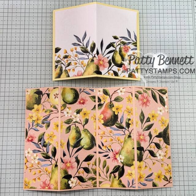 A floral and fruit-themed handmade card is displayed open and closed on a grid background. The design features green pears, yellow and pink flowers, and leafy branches. The closed card shows the pattern at the bottom, while the open card shows the full design. To read more, visit Patty Stamps (pattystamps.com)
