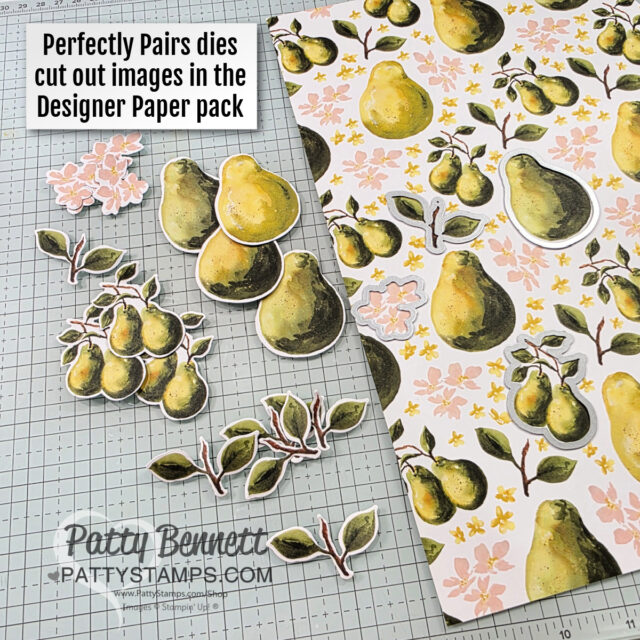 A sheet of patterned paper with pears and flowers is on a grid surface. Next to it are cut-out images of single pears, pear clusters, and leafy branches. A label reads, "Perfectly Pairs dies cut out images in the Designer Paper pack. To read more, visit Patty Stamps (pattystamps.com)