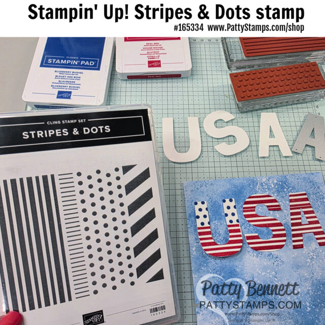 A hand holds the Stampin’ Up! Stripes & Dots cling stamp set over a crafting table with red and blue ink pads, a large rubber stamp, and paper letters spelling “USA” decorated in red, blue, and white. Website and product info are at the top of the image. To read more, visit Patty Stamps (pattystamps.com)