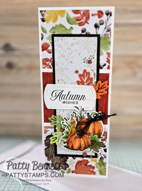 Amber Autumn slimline card for fall. A handmade autumn-themed greeting card features pumpkin and leaf die cuts, layered fall foliage designs, and “Autumn Wishes” in elegant script. The card has rich orange, brown, and green tones on a rustic wood background. “PattyStamps.com” is printed at the bottom. To read more, visit Patty Stamps (pattystamps.com)