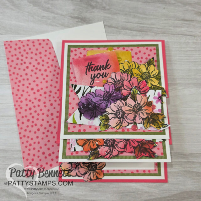 A handmade thank you card features layered panels with colorful stamped flowers in shades of pink, yellow, orange, and purple. The card has a pink background with polka dots, a "thank you" note on top, and matching pink polka dot envelope on a wood surface. To read more, visit Patty Stamps (pattystamps.com)