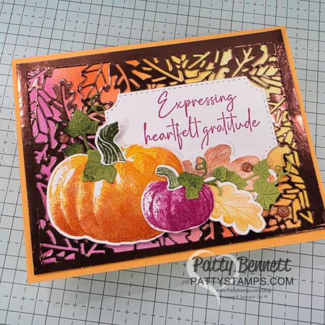 A handmade greeting card featuring layered pumpkins, gourds, and green leaves on a colorful autumn leaf background. The card displays the message "Expressing heartfelt gratitude" in pink script. "PattyStamps.com" is printed at the bottom right corner. To read more, visit Patty Stamps (pattystamps.com)