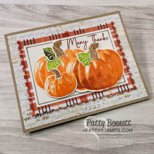 A handmade greeting card featuring three illustrated orange pumpkins with green leaves, layered on plaid and embossed white paper. The card says "Many Thanks" in cursive at the top. The background is a light wood surface. “Patty Bennett PATTYSTAMPS.com” is watermarked. To read more, visit Patty Stamps (pattystamps.com)