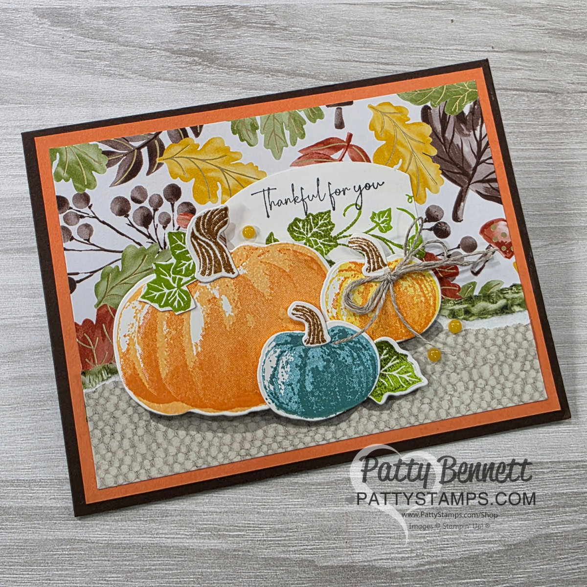 A handmade fall-themed greeting card features illustrated pumpkins in orange, blue, and yellow with green stems, positioned on a textured beige strip. Behind them are patterned leaves and berries. "Thankful for you" is written at the top. The card is signed “Patty Bennett.”. To read more, visit Patty Stamps (pattystamps.com)