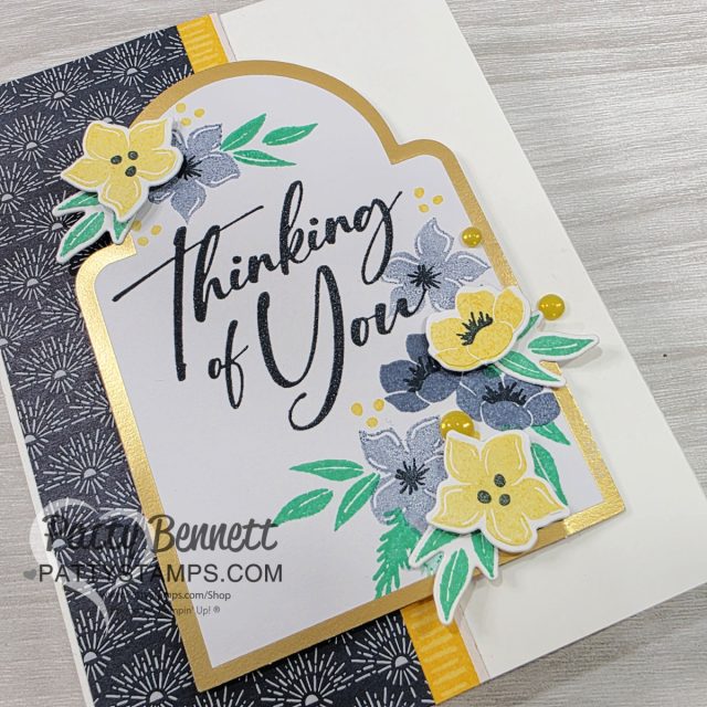 A handmade greeting card features “Thinking of You” in elegant script, surrounded by yellow, black, and gray flowers with green leaves. The layered arch has a gold border, textured black-and-white patterned paper, and yellow accents on a white card base. To read more, visit Patty Stamps (pattystamps.com)