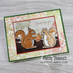 A handmade greeting card featuring two squirrels facing each other, holding an acorn, with "Thankful for you" above them. Perfect for anyone who would say “I Love Squirrels.” Leafy background, green border, and “Patty Bennett PattyStamps.com” at the bottom. To read more, visit Patty Stamps (pattystamps.com)