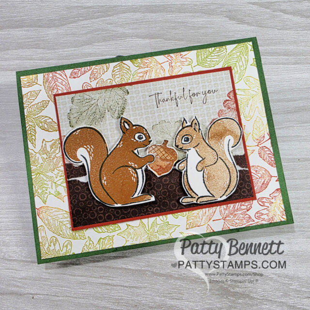 A handmade greeting card featuring two squirrels facing each other, holding an acorn, with "Thankful for you" above them. Perfect for anyone who would say “I Love Squirrels.” Leafy background, green border, and “Patty Bennett PattyStamps.com” at the bottom. To read more, visit Patty Stamps (pattystamps.com)