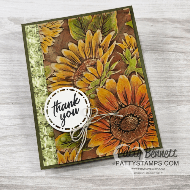Handmade thank you card with a sunflower design in yellow and brown shades, accented with a green patterned strip on the left. A round, white tag with "thank you" in script is tied with twine and accented with green dots. Text "Patty Bennett" at bottom. To read more, visit Patty Stamps (pattystamps.com)