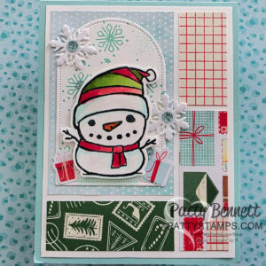 A handmade holiday card features a cheerful snowman in a red and green hat, red scarf, and stick arms, surrounded by snowflakes and presents. The card has festive patterned panels and a “Patty Stamps” watermark in the bottom right corner. To read more, visit Patty Stamps (pattystamps.com)