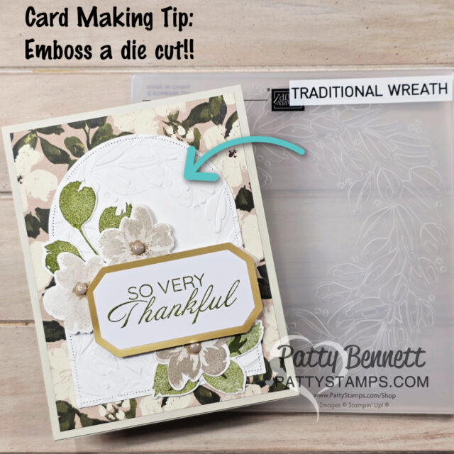 Petals of Beauty card. A handmade card with floral designs and “SO VERY Thankful” on a layered hexagon shape is shown. An arrow points to the embossed white die-cut background. Behind the card is a clear embossing folder labeled “TRADITIONAL WREATH.” Text reads: “Card Making Tip: Emboss a die cut!!”. To read more, visit Patty Stamps (pattystamps.com)