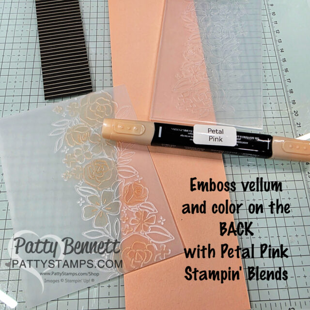 A translucent vellum sheet embossed with floral designs lies on a crafting mat, partially colored on the back with a dual-tip “Petal Pink” Stampin’ Blends marker. Peach cardstock, a striped paper, and embossing tools surround the project. Text instructions are shown. To read more, visit Patty Stamps (pattystamps.com)