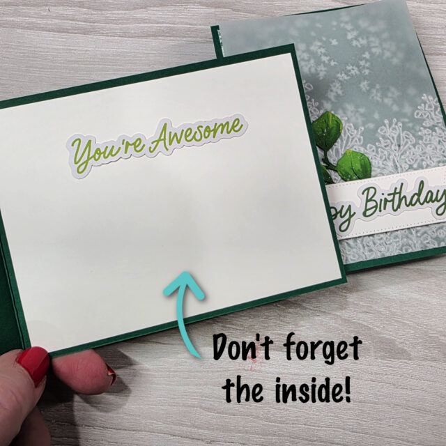 A hand with red nail polish holds open a green greeting card. Inside, “You’re Awesome” is written in green script. An arrow points to the blank space below, with the text “Don’t forget the inside!” in black near the bottom right corner. To read more, visit Patty Stamps (pattystamps.com)