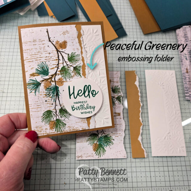 A hand holds a greeting card with pine branch artwork and text reading “Hello Happiest Birthday Wishes.” Next to the card are strips of white embossed paper and brown cardstock. Overlay text reads: “Peaceful Greenery embossing folder.”. To read more, visit Patty Stamps (pattystamps.com)