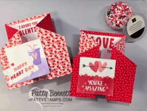 Two handmade Valentine’s Day Fun Fold Cards feature red and pink heart patterns and uplifting messages. One says “Happy Heart Day” with a purple drink; the other, “You’re Amazing,” has arrows and hearts. A dish of colorful sprinkles sits nearby. To read more, visit Patty Stamps (pattystamps.com)