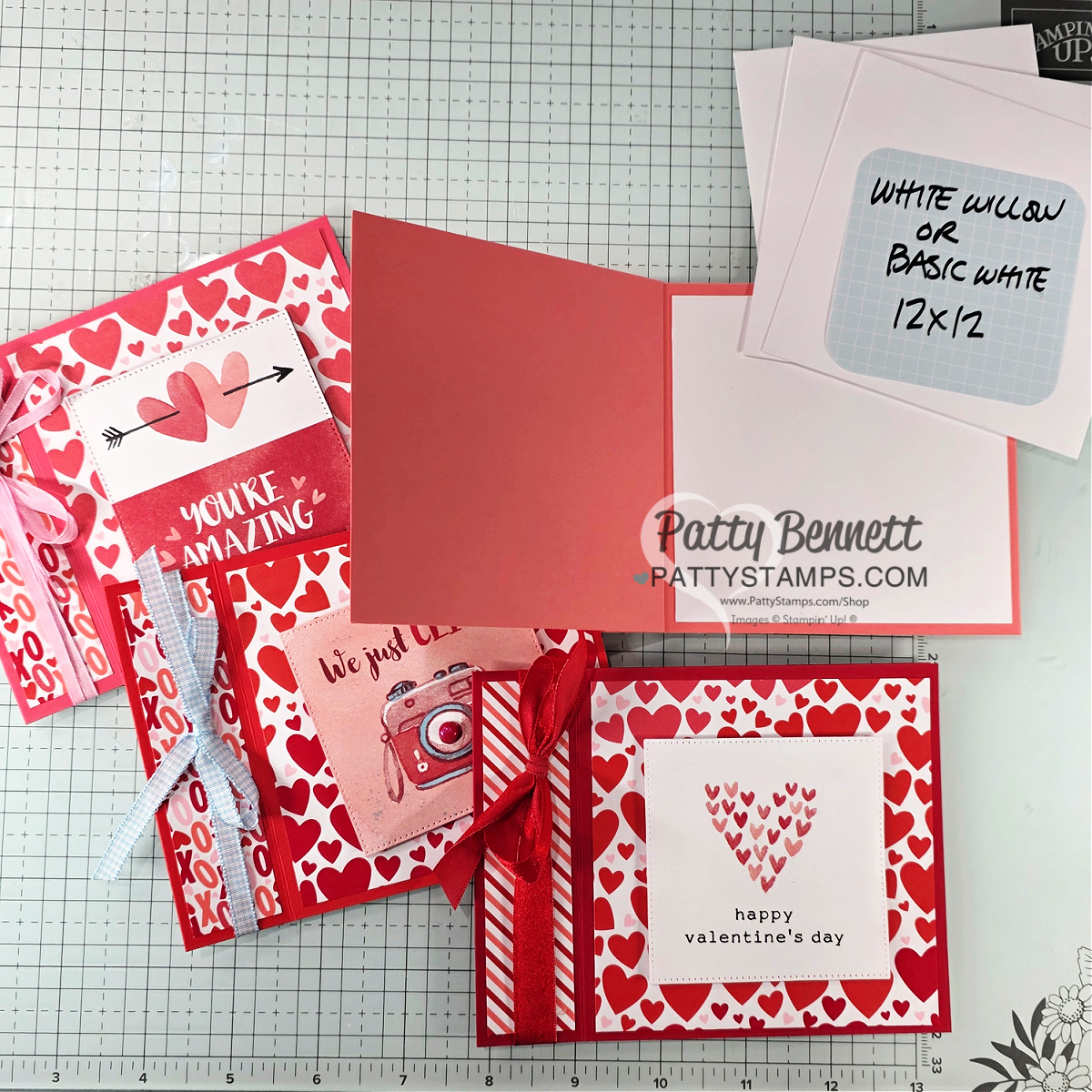 Four handmade Valentine’s Day cards with red, pink, and heart patterns are displayed. One card is open, showing a blank inside. There are white 12x12 papers in the corner, and a grid mat background. “Patty Bennett PATTYSTAMPS.com” is labeled on the photo. To read more, visit Patty Stamps (pattystamps.com)