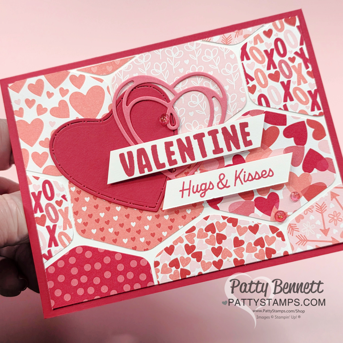 A handmade Valentine’s Day card features various pink and red heart and “XO” patterns, topped with layered die-cut hearts and bold text reading “VALENTINE” and “Hugs & Kisses.” The creator’s watermark, “Patty Bennett,” appears in the bottom right corner. To read more, visit Patty Stamps (pattystamps.com)