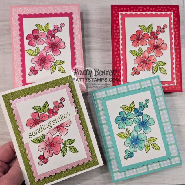 Four handmade greeting cards are displayed, each featuring hand-colored floral designs with green leaves. The cards have pink, red, green, or blue frames and backgrounds, with one card reading “sending smiles” on a white banner. A watermark says "Patty Bennett’s PattyStamps.com". To read more, visit Patty Stamps (pattystamps.com)