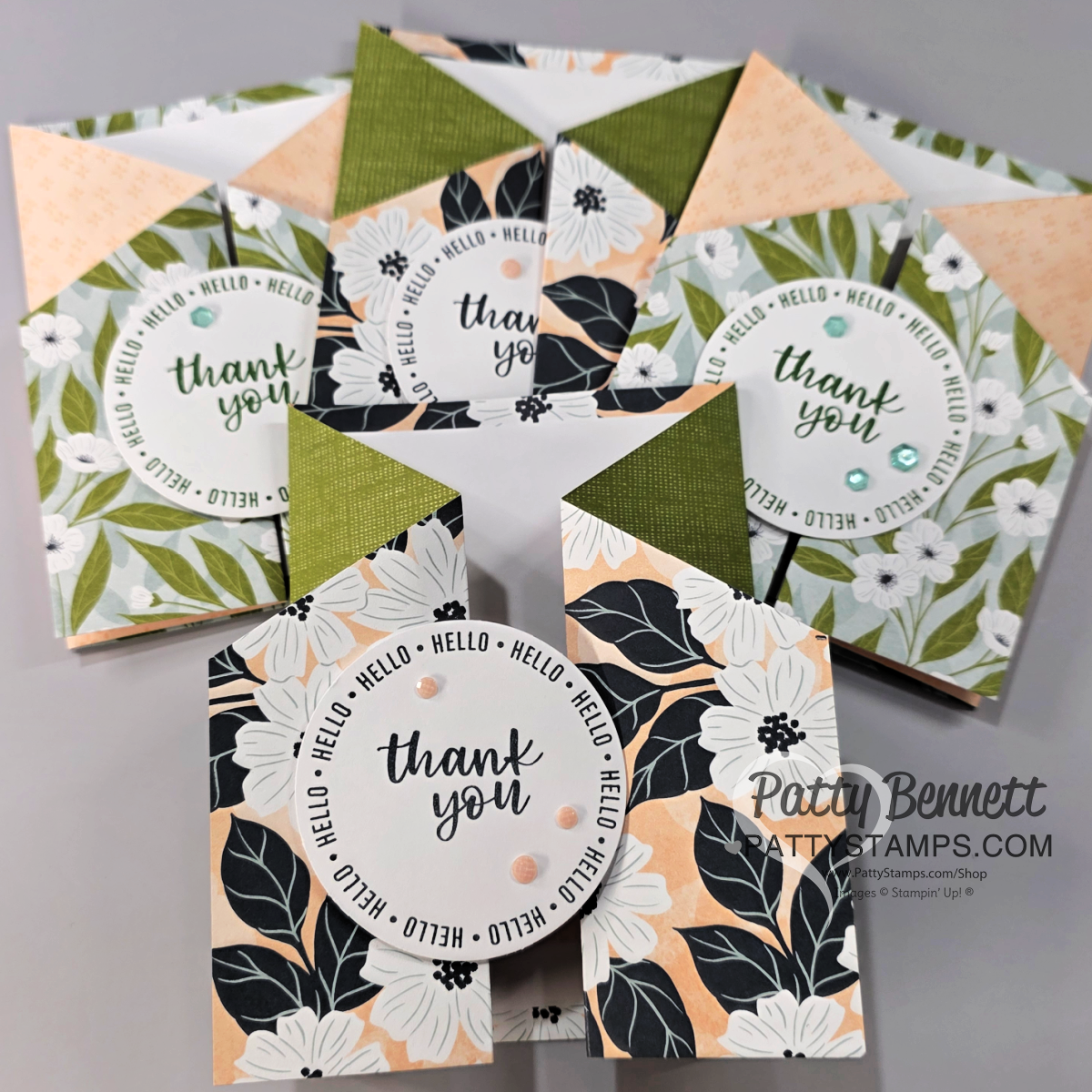 A set of handmade floral thank you cards arranged in a fan shape. Each card features black, white, and peach flowers with green accents and circular “thank you” messages. Some cards have decorative gems and geometric folding. The “Patty Bennett” watermark is visible. To read more, visit Patty Stamps (pattystamps.com)