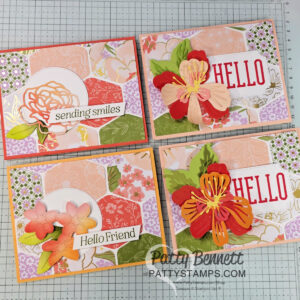 Four handmade greeting cards with floral designs, pastel colors, and layered paper embellishments. Two cards say "HELLO" with bold flowers, one says "sending smiles" with a rose, and another says "Hello Friend" with pink flowers. Cards are on a grid workspace. To read more, visit Patty Stamps (pattystamps.com)