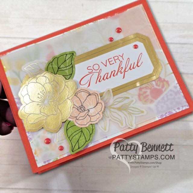 Cards for Spring: A handmade card with “So Very Thankful” in red script on a gold-edged label. Gold and peach flowers with green leaves decorate the left side. Red pearls accent the card. Background is soft floral patterns. “Patty Bennett” watermark at the bottom right. To read more, visit Patty Stamps (pattystamps.com)