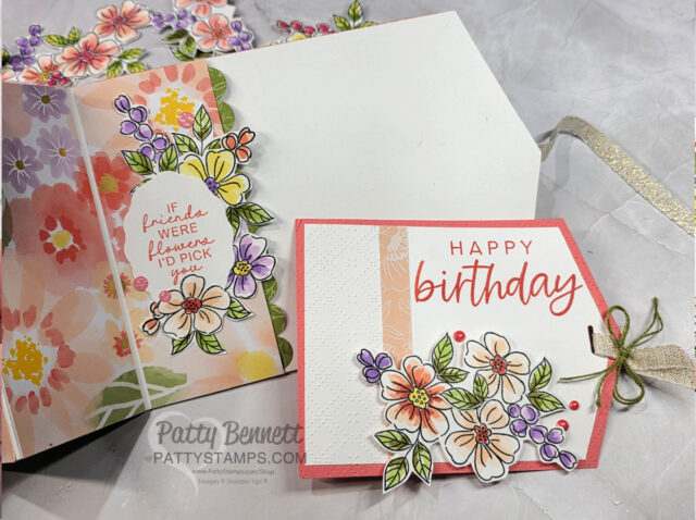 Two handmade floral birthday cards are displayed. The left card is partially open with pastel flowers and the text, “If friends were flowers, I’d pick you.” The right card, layered in pink, says “Happy birthday” and features colorful floral embellishments and a ribbon. To read more, visit Patty Stamps (pattystamps.com)