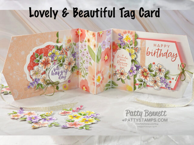 A handmade, multicolored floral tag card with three panels sits open. Each panel features layered die-cut flowers, leaves, and birthday greetings. The background is pastel with floral designs, and the card is accented with small bows and ribbon on a light surface. To read more, visit Patty Stamps (pattystamps.com)