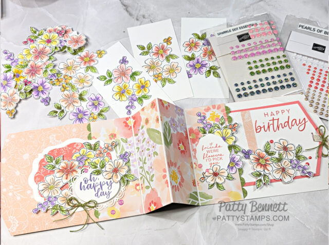 A handmade birthday card and its components are displayed on a white surface. The card features pastel floral patterns, cut-out flowers, and messages like "on happy day" and "Happy birthday." There are also adhesive pearls, stamped flowers, and colored embellishments. To read more, visit Patty Stamps (pattystamps.com)