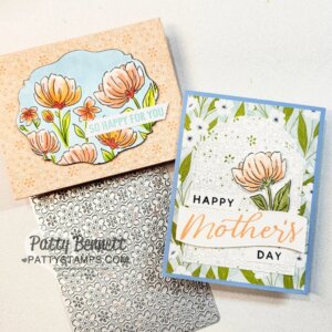 Two handmade Mother's Day cards with floral designs are shown. One card is peach with illustrated orange flowers and reads “So happy for you.” The other is blue and white with floral patterns and says “Happy Mother’s Day.” A floral metal die sits below. To read more, visit Patty Stamps (pattystamps.com)