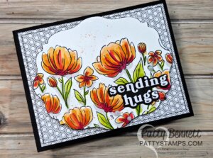 A handmade card features bright orange and yellow watercolor flowers with green leaves, a honeycomb-patterned background, and the bold white text “sending hugs” outlined in black. The card rests on a wooden surface. To read more, visit Patty Stamps (pattystamps.com)