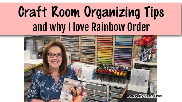 A smiling woman with glasses stands in a craft room, holding a magazine. Behind her are neatly organized shelves of paper, ink pads, and craft supplies sorted in rainbow order. The top banner reads, "Craft Room Organizing Tips and why I love Rainbow Order. To read more, visit Patty Stamps (pattystamps.com)