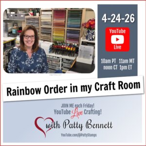 A woman with glasses and shoulder-length brown hair smiles at a desk in a colorful craft room. Behind her are neatly organized shelves of craft supplies and inks in rainbow order. Text advertises a YouTube Live on 4-24-26 about organizing craft supplies by color. To read more, visit Patty Stamps (pattystamps.com)