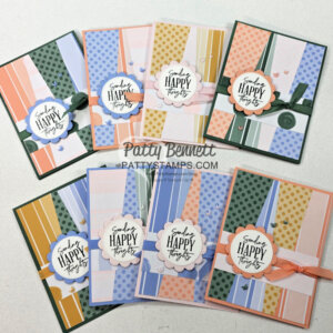 Eight handmade greeting cards are arranged on a white surface. Each card features colorful, patterned paper strips, bows, and a central scalloped circle with the message “Sending Happy Thoughts.” The designs use pastel and bold colors with polka dots and stripes. To read more, visit Patty Stamps (pattystamps.com)