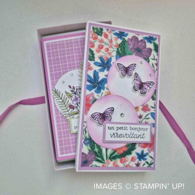A floral-decorated rectangular gift box with a pink ribbon is open, revealing two layered cards inside. The top card features purple butterflies, pink circles, flowers, and French text labels. Branding “IMAGES © STAMPIN’ UP!” appears in the bottom right corner. To read more, visit Patty Stamps (pattystamps.com)