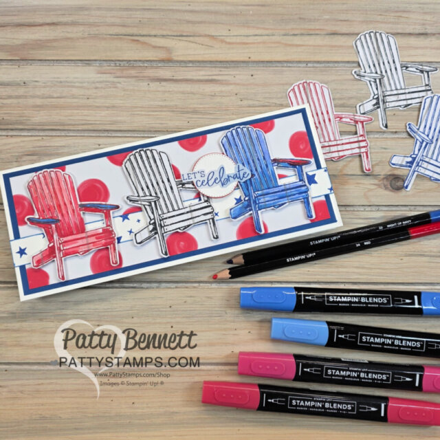 A handmade slimline card features three Adirondack chairs colored red, white, and blue, with "Let's celebrate" text. Red polka dots and blue stars decorate the background. Stampin’ Blends markers and colored pencils are arranged nearby on a wooden table. To read more, visit Patty Stamps (pattystamps.com)
