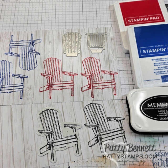 A craft workspace displays stamped and die-cut Adirondack chair images in red, blue, and black on wood-patterned paper. Nearby are blue and red Stampin’ Up! ink pads, a black Memento ink pad, and a metal chair die. PattyStamps.com is watermarked. To read more, visit Patty Stamps (pattystamps.com)