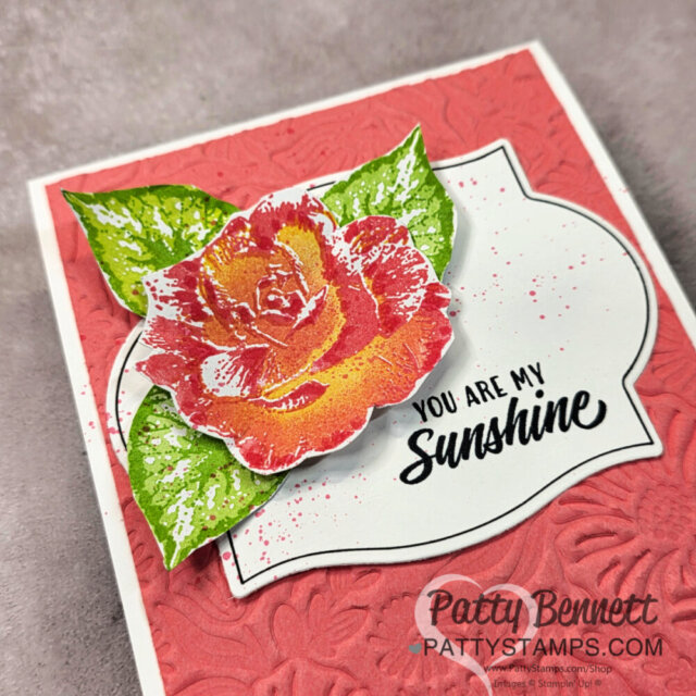 Handmade card with a large red and yellow rose and green leaves on an embossed red background. The rose sits atop a white label with the text "YOU ARE MY Sunshine." "Patty Bennett PattyStamps.com" is watermarked at the lower right. To read more, visit Patty Stamps (pattystamps.com)