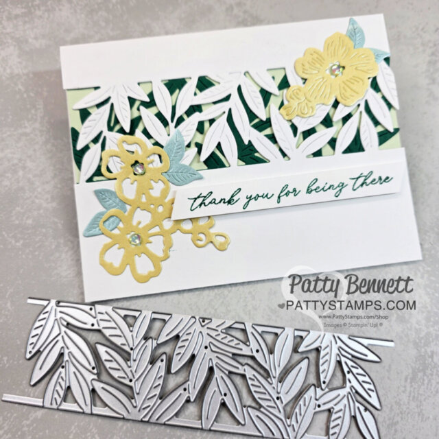 A handmade card features layered die-cut leaves in white and green tones, accented with yellow and light blue flowers, with gems at the centers. A white strip reads “thank you for being there” in green script. Below is a metal leaf-pattern die. “Patty Bennett” watermark at bottom. To read more, visit Patty Stamps (pattystamps.com)