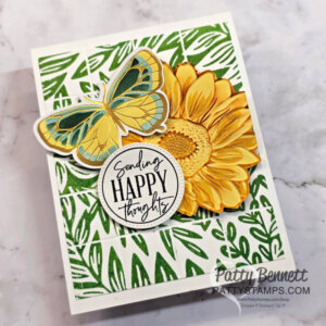Handmade card with green leafy background, large yellow sunflower, blue-yellow butterfly, and round tag reading “Sending HAPPY thoughts.” Card is angled on a marble surface. “Patty Bennett” and her website watermark appear in the bottom right corner. To read more, visit Patty Stamps (pattystamps.com)