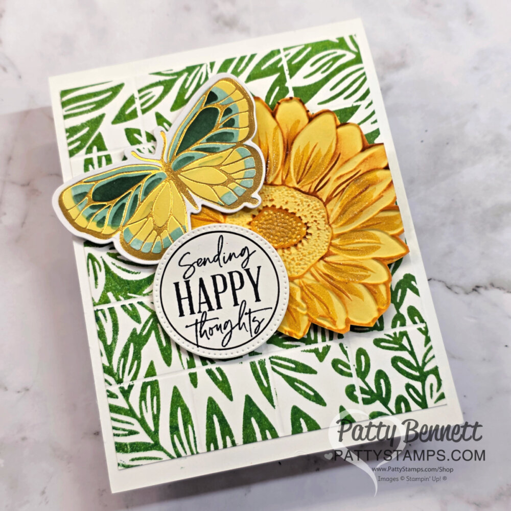 Handmade card with green leafy background, large yellow sunflower, blue-yellow butterfly, and round tag reading “Sending HAPPY thoughts.” Card is angled on a marble surface. “Patty Bennett” and her website watermark appear in the bottom right corner. To read more, visit Patty Stamps (pattystamps.com)