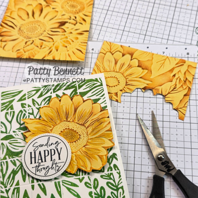 Handmade sunflower card with leafy green background, sentiment reading "Sending Happy Thoughts." Nearby are scissors and a yellow embossed sunflower panel with a cut edge, all on a gridded work surface labeled Patty Bennett, pattystamps.com. To read more, visit Patty Stamps (pattystamps.com)