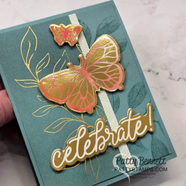 A teal greeting card features gold-embossed leaves, two butterflies—one large pink and gold, one small pink and gold—and the word "celebrate!" in gold and white script. A vertical striped accent and Patty Bennett's logo appear at the bottom right. To read more, visit Patty Stamps (pattystamps.com)
