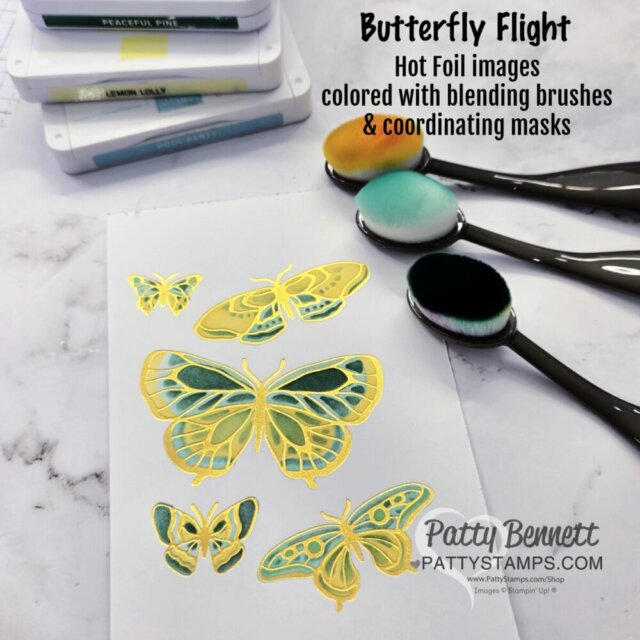 A white card features three green and yellow hot foil butterflies. Three colorful blending brushes and ink pads are nearby. Text on the image explains the use of hot foil images, blending brushes, and coordinating masks. PattyStamps.com is credited. To read more, visit Patty Stamps (pattystamps.com)